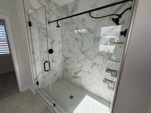 Full bathroom featuring a marble finish shower and light tile patterned floors
