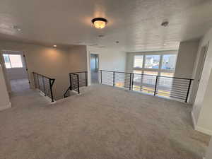 Unfurnished room with a textured ceiling, carpet floors, plenty of natural light, and a smoke detector
