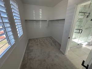 Walk in closet featuring light colored carpet and light tile patterned flooring