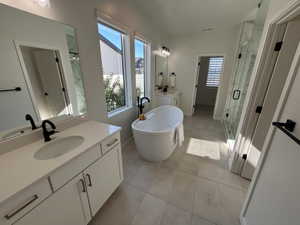 Full bathroom with two vanities, a marble finish shower, healthy amount of natural light, and a freestanding tub