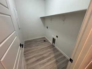 Laundry area with light wood-style floors, electric dryer hookup, and electric panel