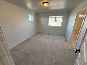 Unfurnished bedroom featuring light colored carpet and a textured ceiling