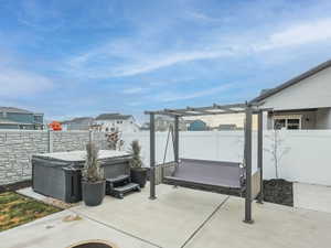 Fenced backyard with a residential view, a patio, a hot tub, and a pergola