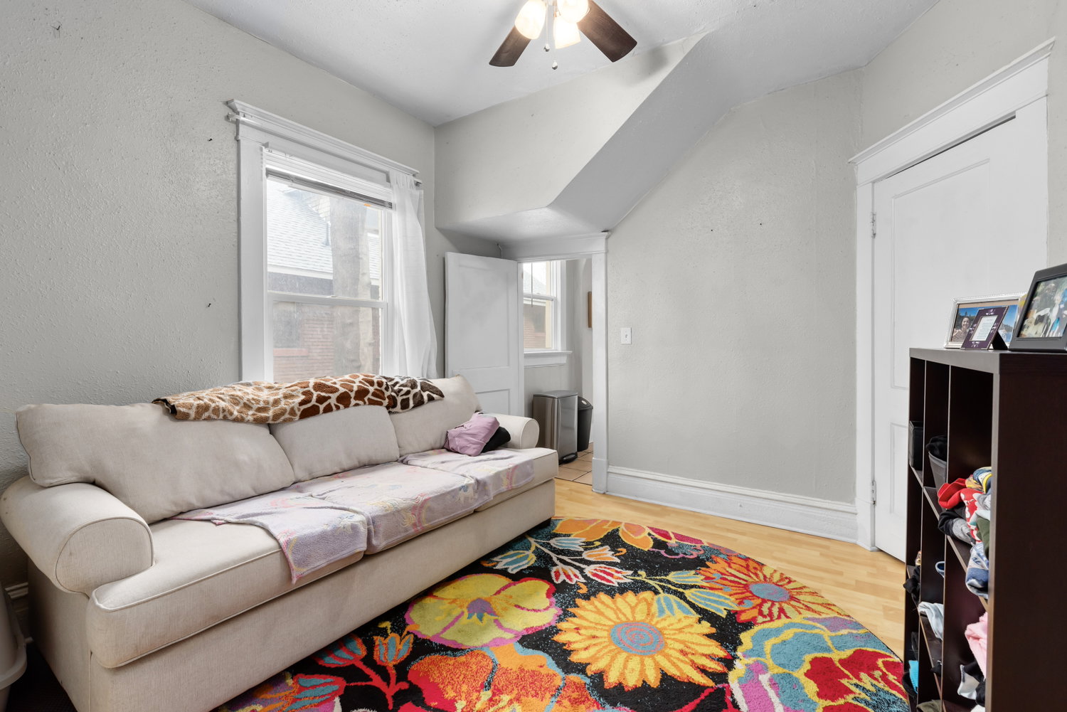 Living room with light wood finished floors, ceiling fan, and vaulted ceiling