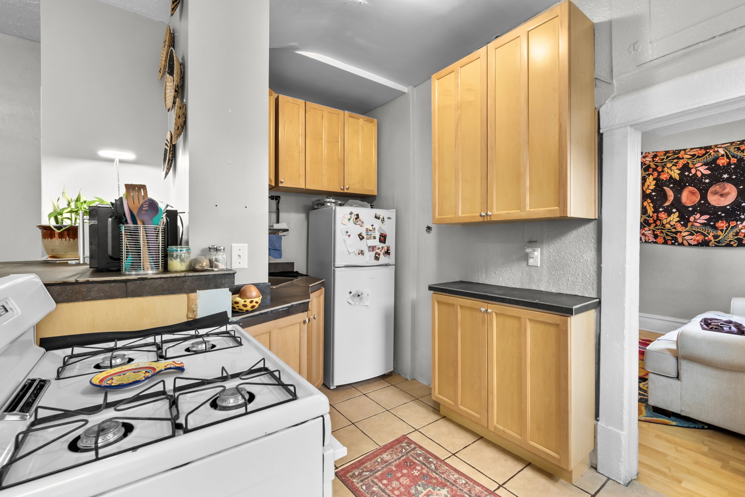 Kitchen with white appliances, light wood finish cabinets, and light tile patterned floors