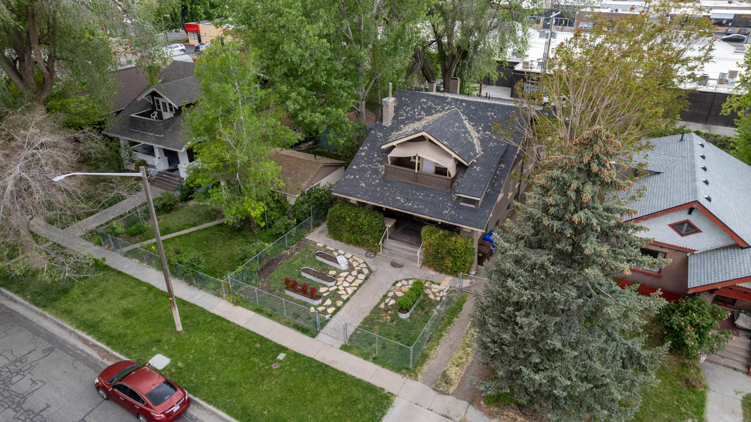 Craftsman-style home featuring a covered front porch, dormer with balcony, and mature trees