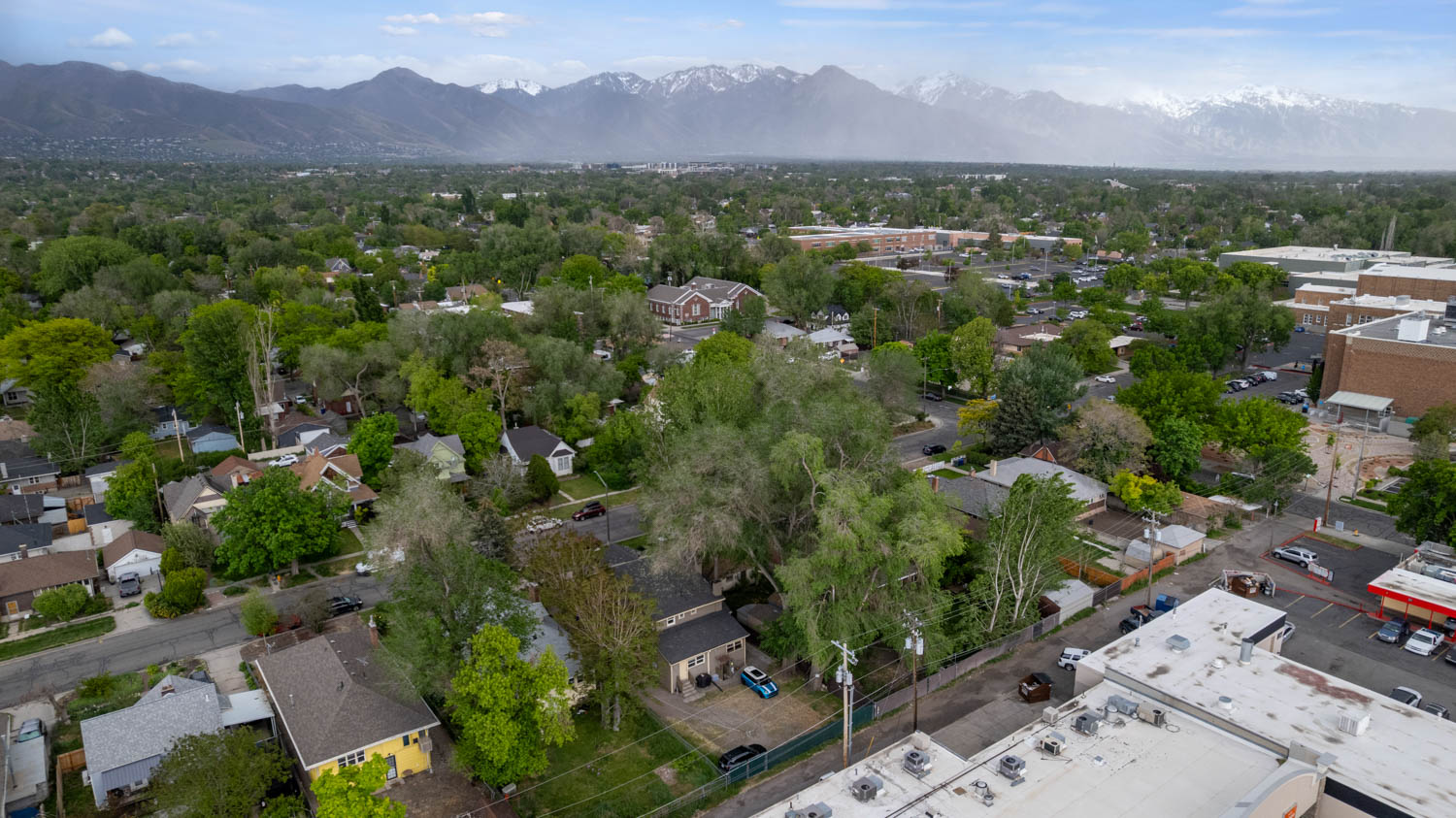 Aerial perspective showcasing a residential area with mature tree coverage, surrounded by a mountain backdrop