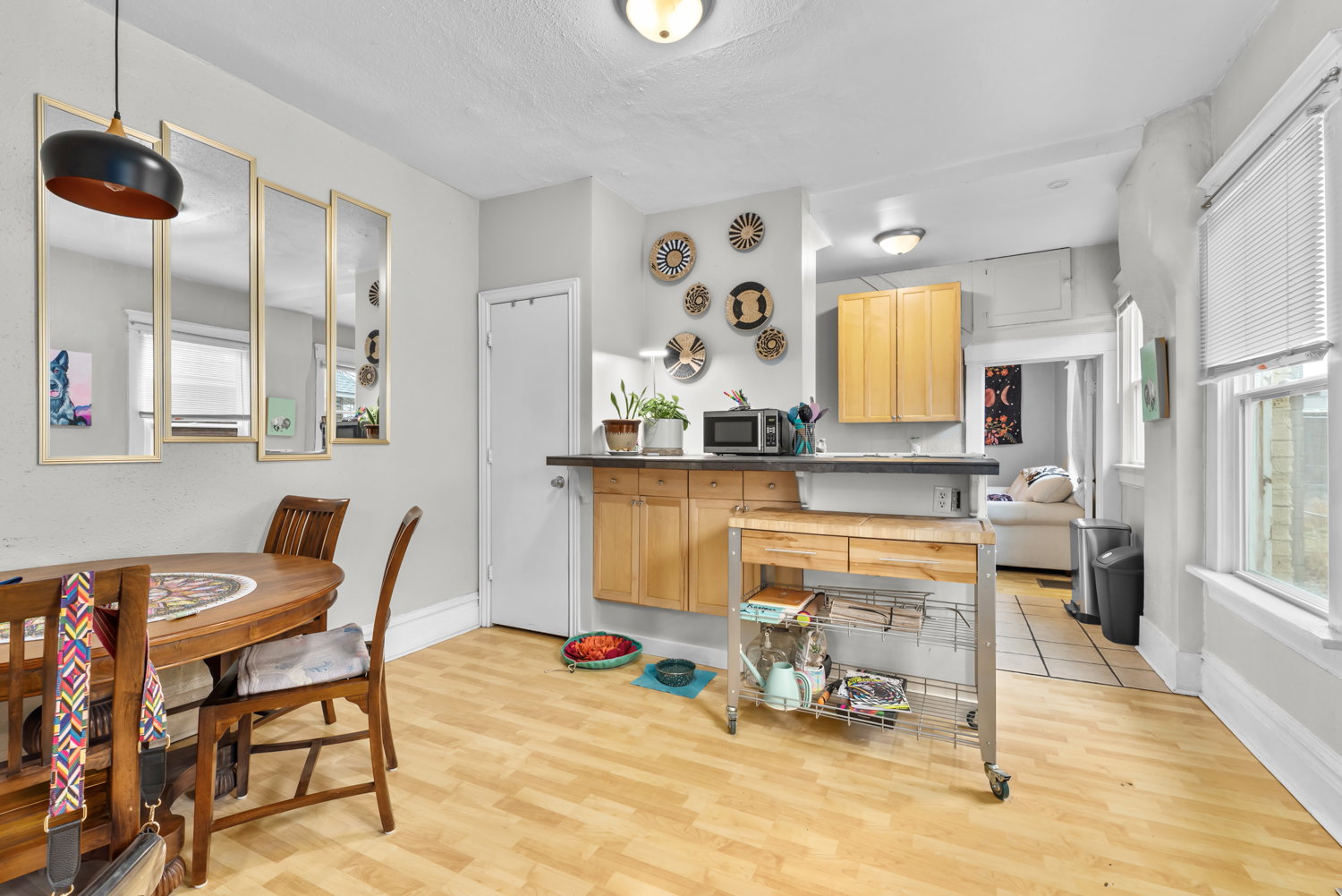 Kitchen with light wood finish cabinetry, plenty of natural light, light wood-type flooring, and dark countertops