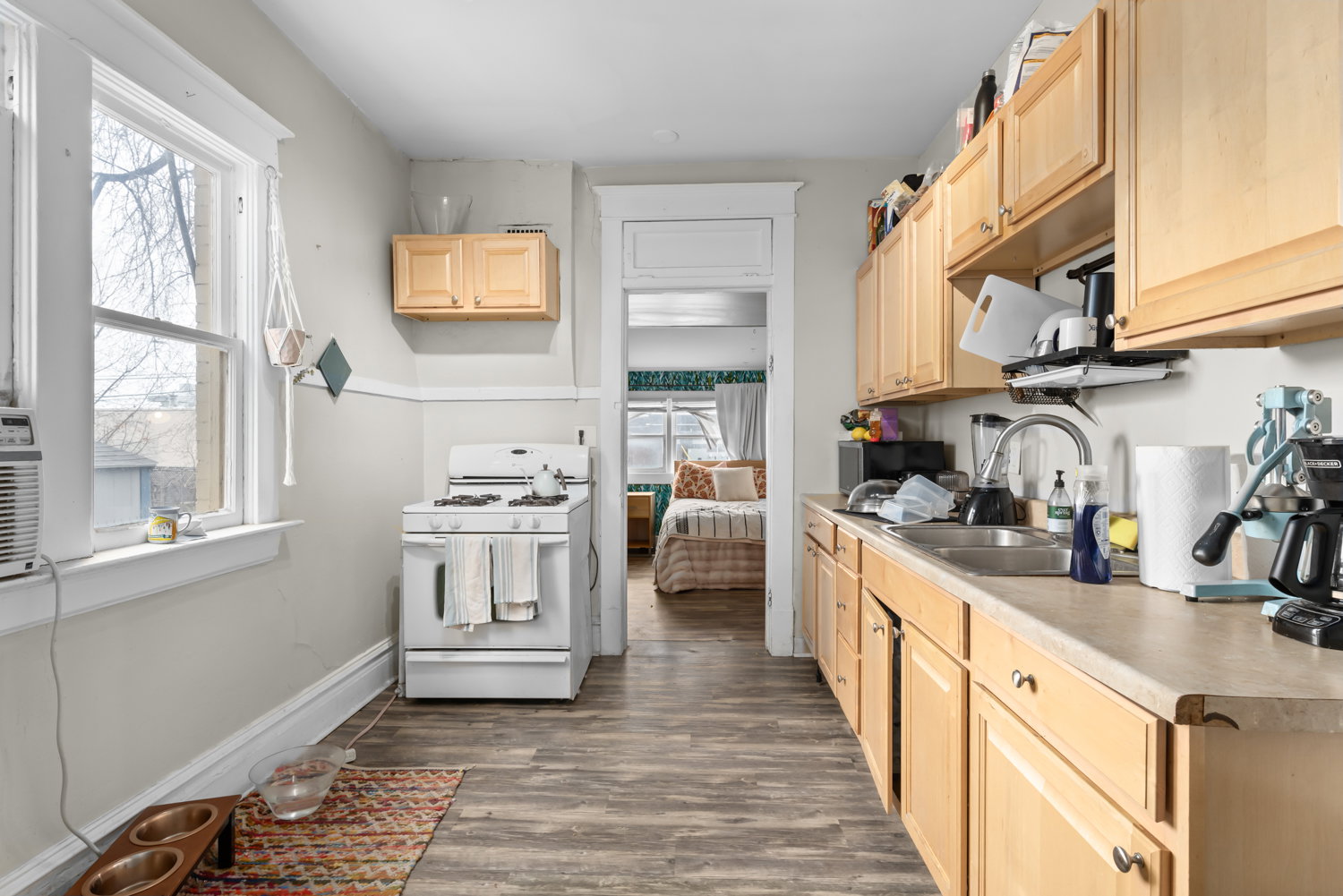 Kitchen with light wood finish cabinetry, white range with gas stovetop, light countertops, dark wood finished floors, and stainless steel microwave