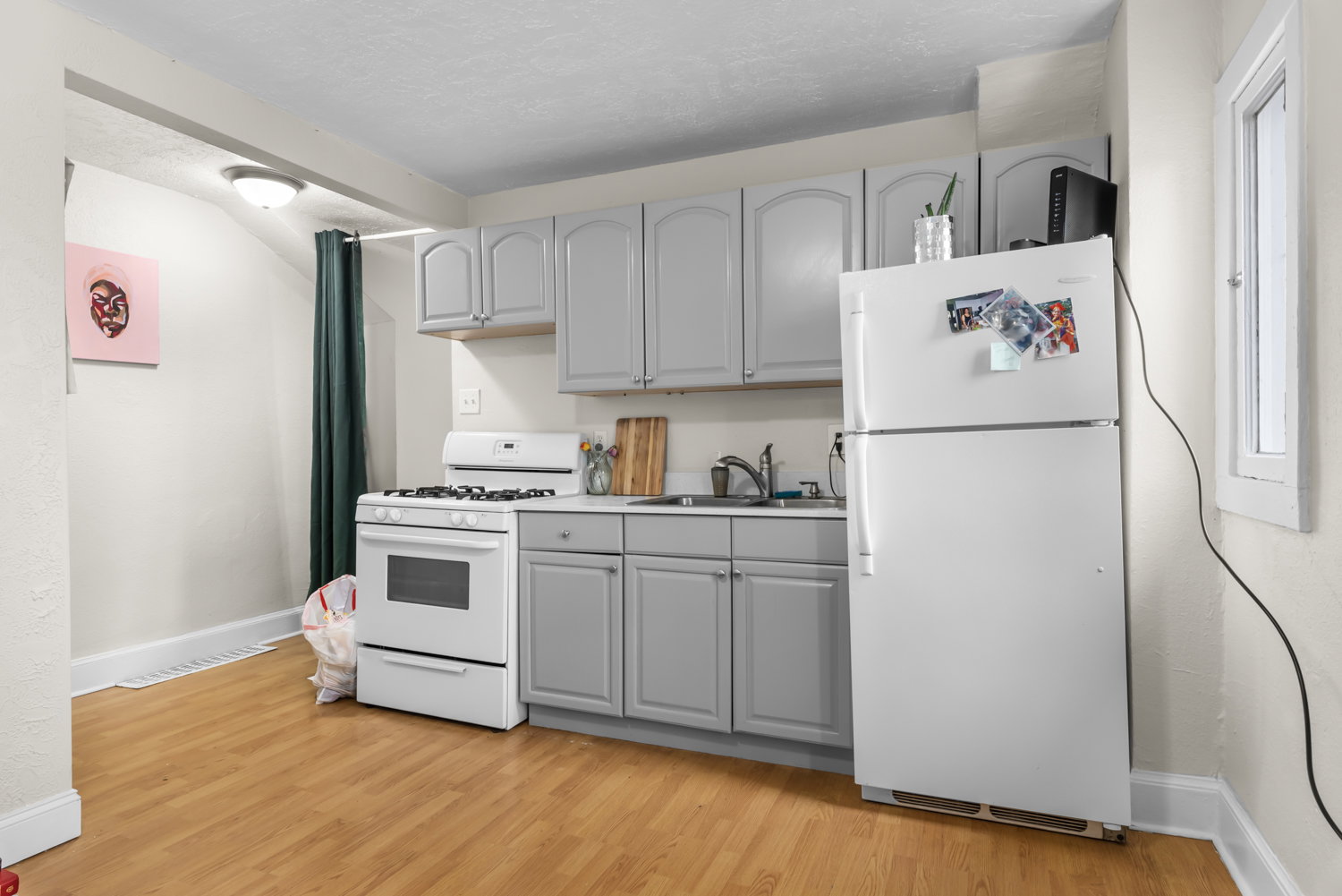 Kitchen featuring white appliances, gray cabinets, light countertops, light wood finished floors, and a textured ceiling