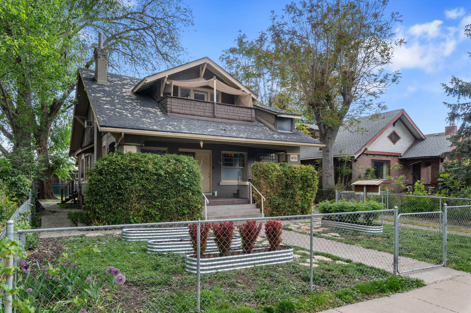 Craftsman-style exterior featuring a covered front porch, an upper-level balcony, and mature trees providing natural shade