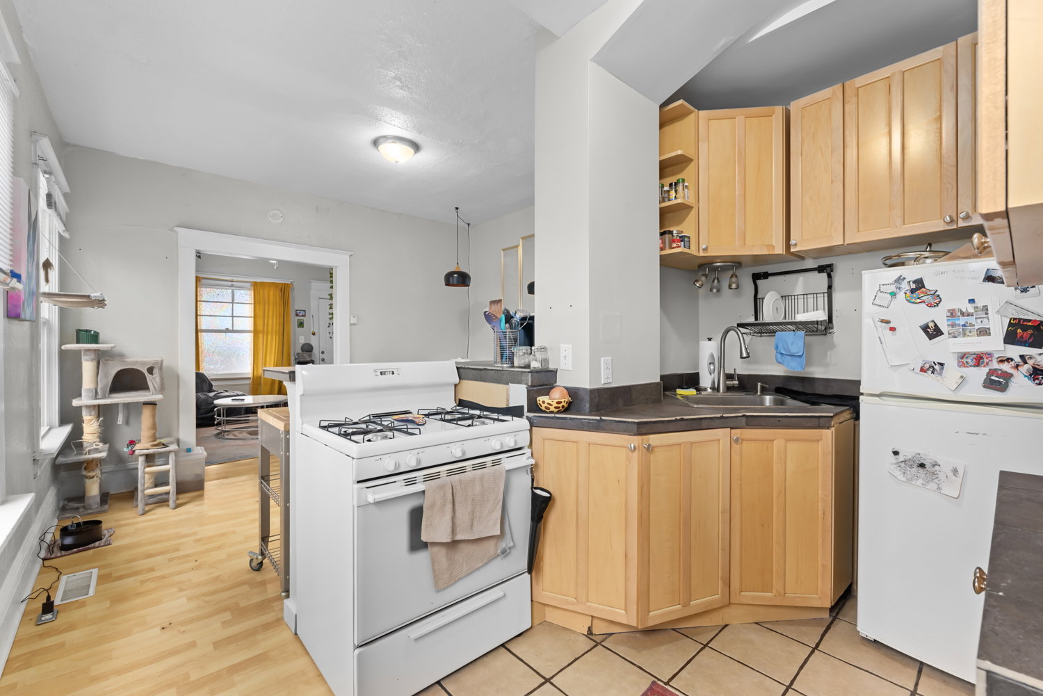 Kitchen with light wood finish cabinets, white appliances, open shelves, and a peninsula