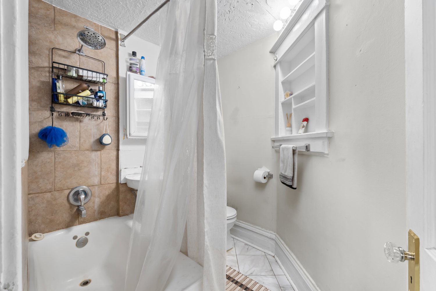 Bathroom featuring a textured ceiling and shower / bath combo with shower curtain