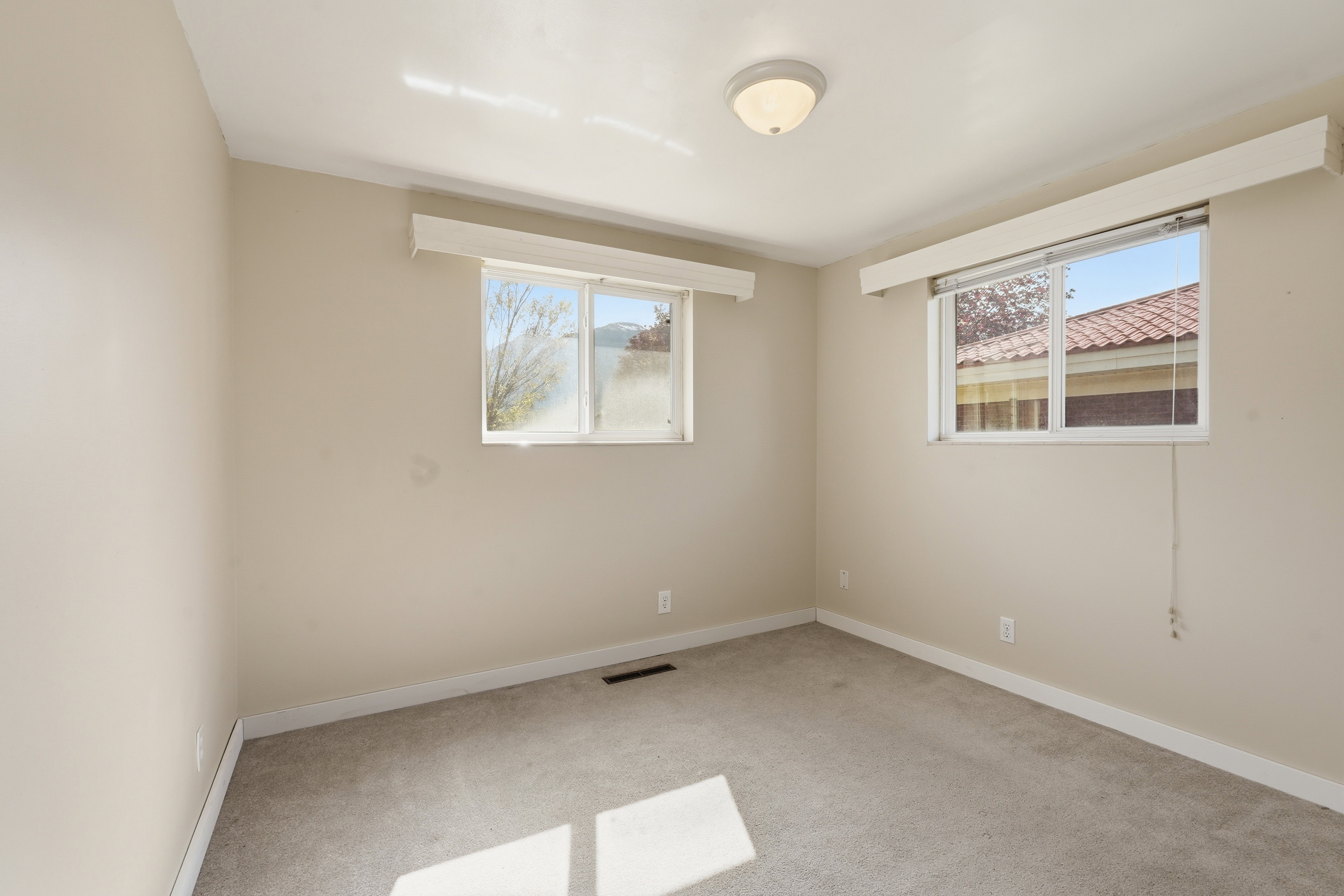 Unfurnished room featuring light carpet and baseboards