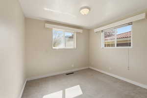 Unfurnished room featuring light carpet and baseboards