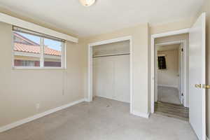 Unfurnished bedroom featuring light carpet and a closet