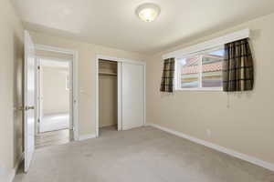 Unfurnished bedroom with light colored carpet and a closet