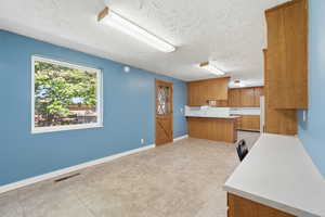 Kitchen with light countertops, wood finish cabinetry, a peninsula, a breakfast bar area, and light tile patterned floors