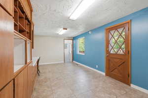 Entryway with light tile patterned flooring and a textured ceiling