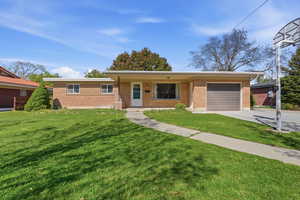 Single story home with a garage, brick siding, a front lawn, and driveway