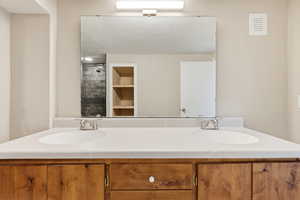 Full bathroom with double vanity and tiled shower