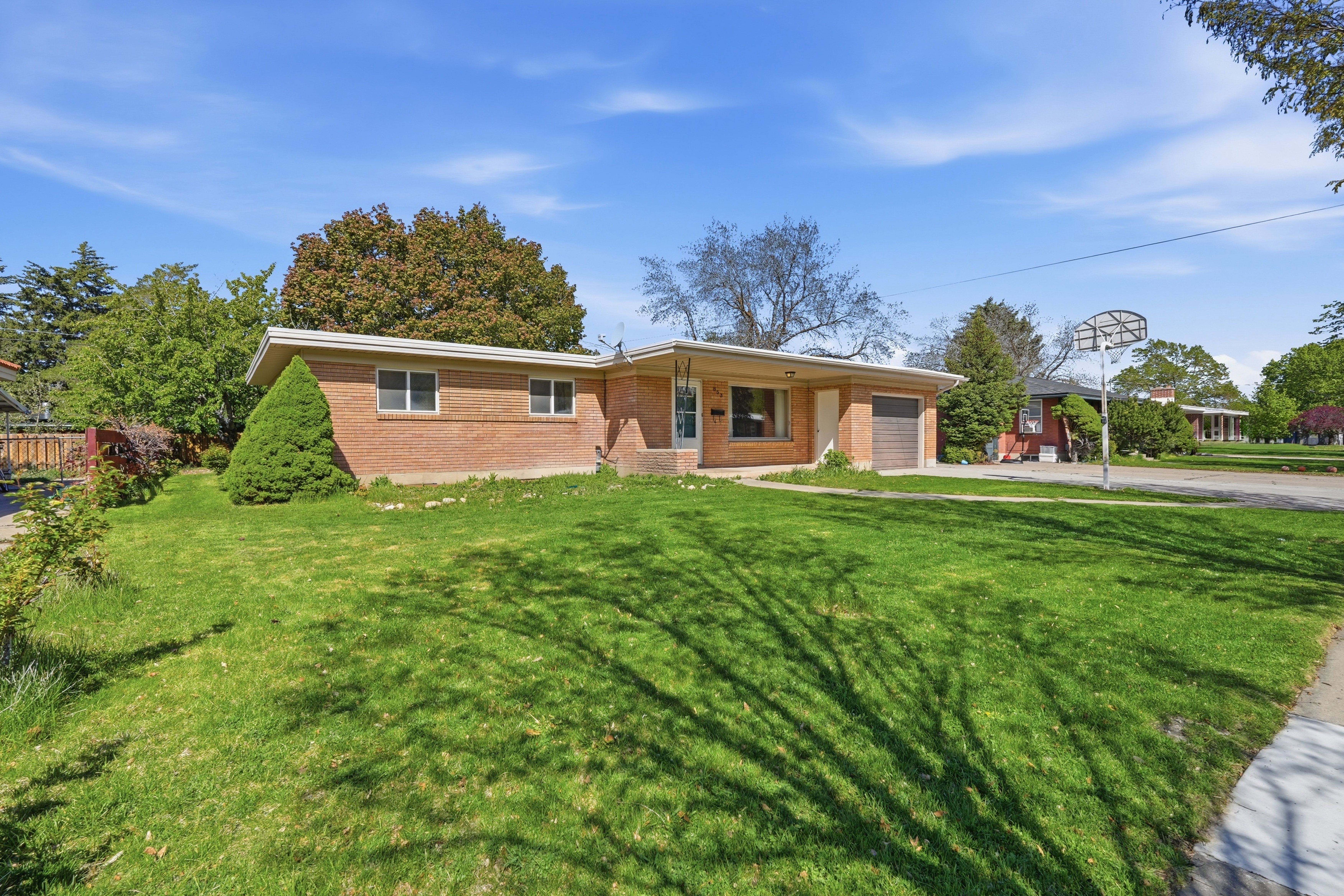 Ranch-style house featuring a garage, brick siding, driveway, and a front yard