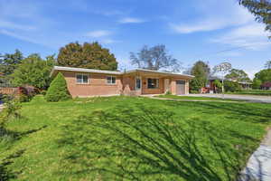 Ranch-style house featuring a garage, brick siding, driveway, and a front yard