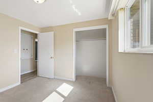 Unfurnished bedroom with light colored carpet and a closet
