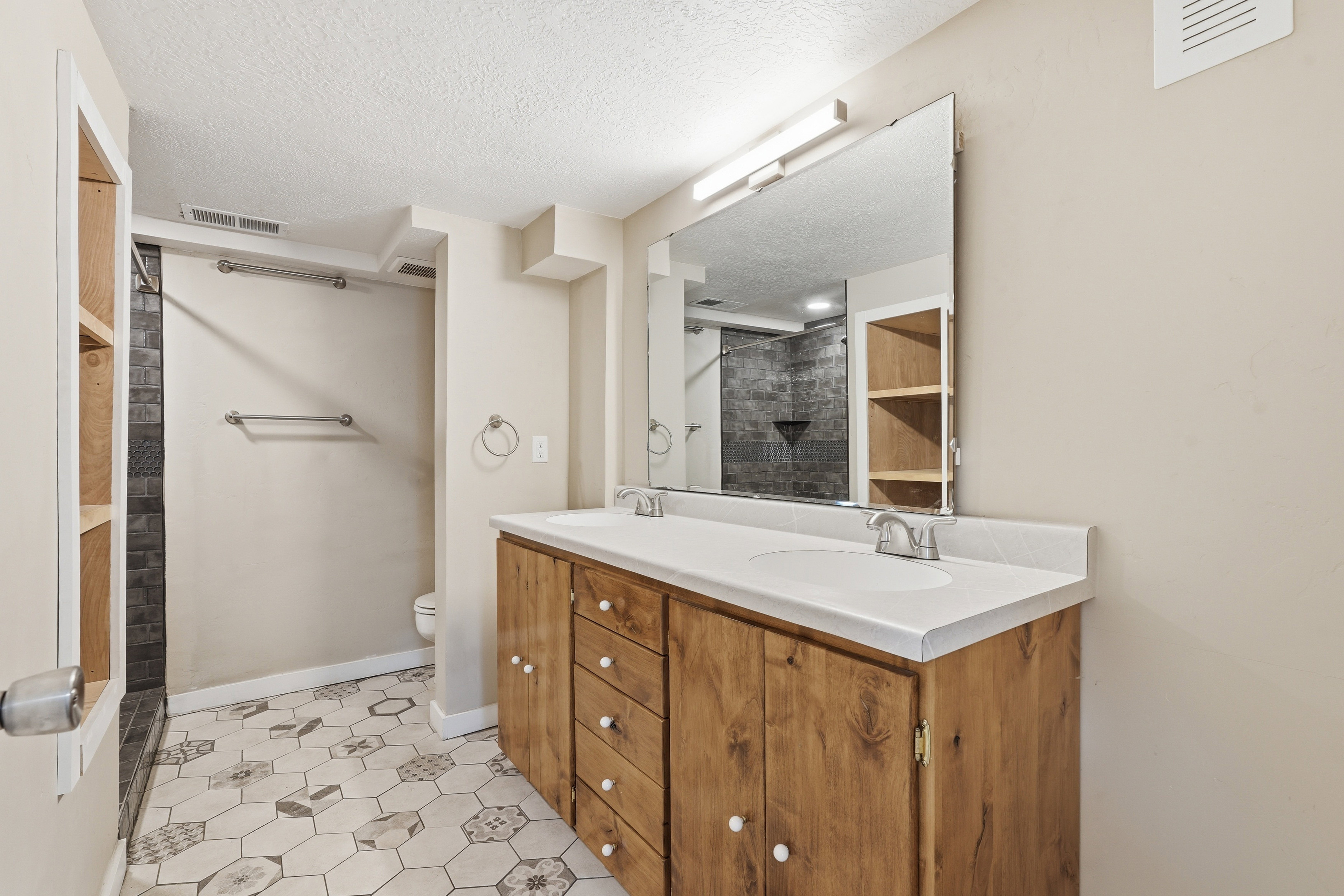 Full bathroom with double vanity, light tile patterned floors, and a textured ceiling