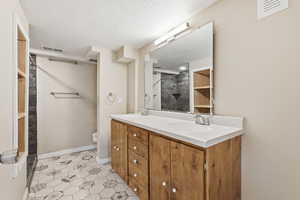 Full bathroom with double vanity, light tile patterned floors, and a textured ceiling