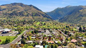 Aerial view of property and surrounding area featuring a mountain backdrop and nearby suburban area