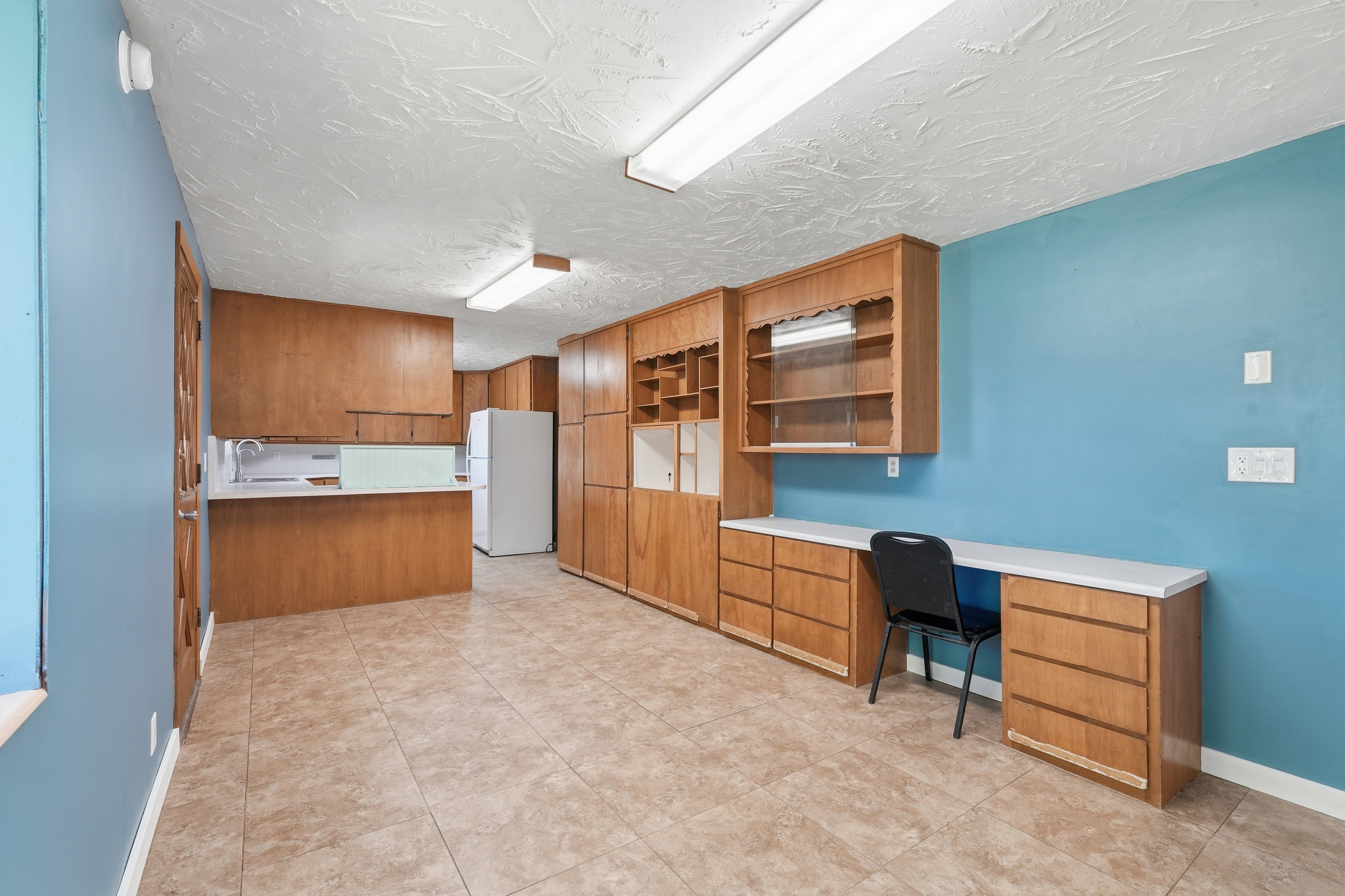 Unfurnished office with built in study area, light tile patterned flooring, and a textured ceiling