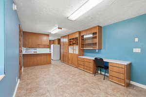 Unfurnished office with built in study area, light tile patterned flooring, and a textured ceiling