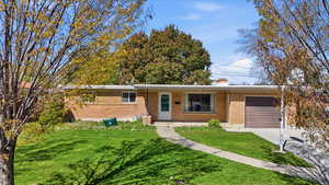 Ranch-style home featuring an attached garage, a front yard, brick siding, and concrete driveway
