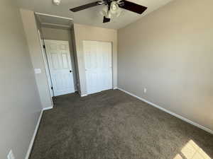 Unfurnished bedroom with dark carpet, ceiling fan, and a closet
