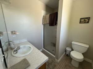 Full bathroom with vanity, a shower stall, and dark tile patterned flooring