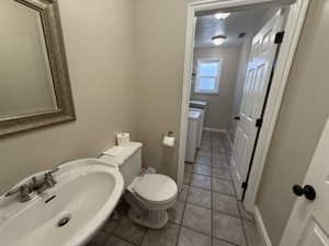Half bath featuring light tile patterned floors, washing machine and clothes dryer, and a textured ceiling
