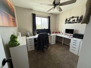 Home office with dark carpet and ceiling fan