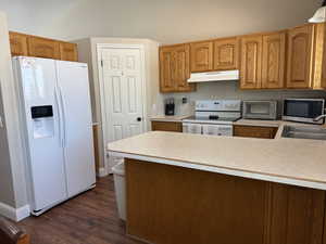 Kitchen featuring white appliances, light countertops, wood finish cabinets, and dark wood-style floors