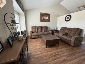 Living room with dark wood-style flooring and vaulted ceiling