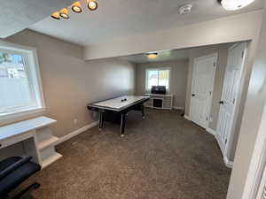 Playroom with dark carpet and a textured ceiling