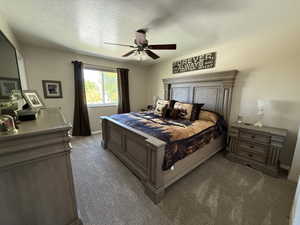 Carpeted bedroom featuring a textured ceiling and a ceiling fan