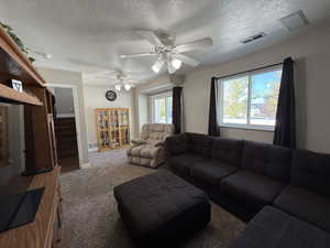 Carpeted living area with a textured ceiling and a ceiling fan
