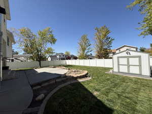Fenced backyard featuring a patio area, a shed, and a residential view