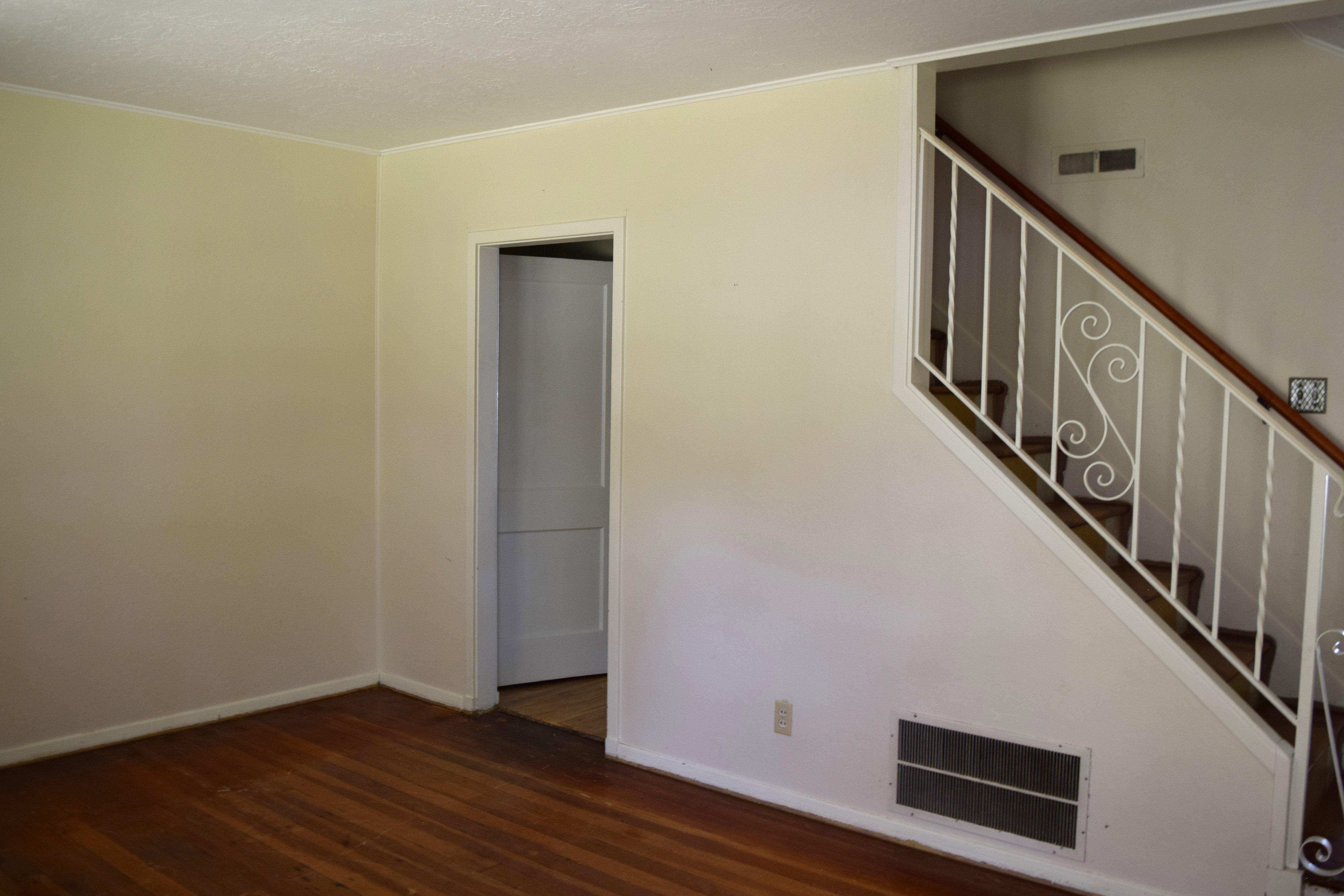 Unfurnished living room featuring dark wood-style floors and ornamental molding