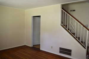 Unfurnished living room featuring dark wood-style floors and ornamental molding