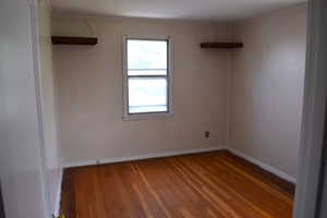 Empty room with wood-type flooring and baseboards
