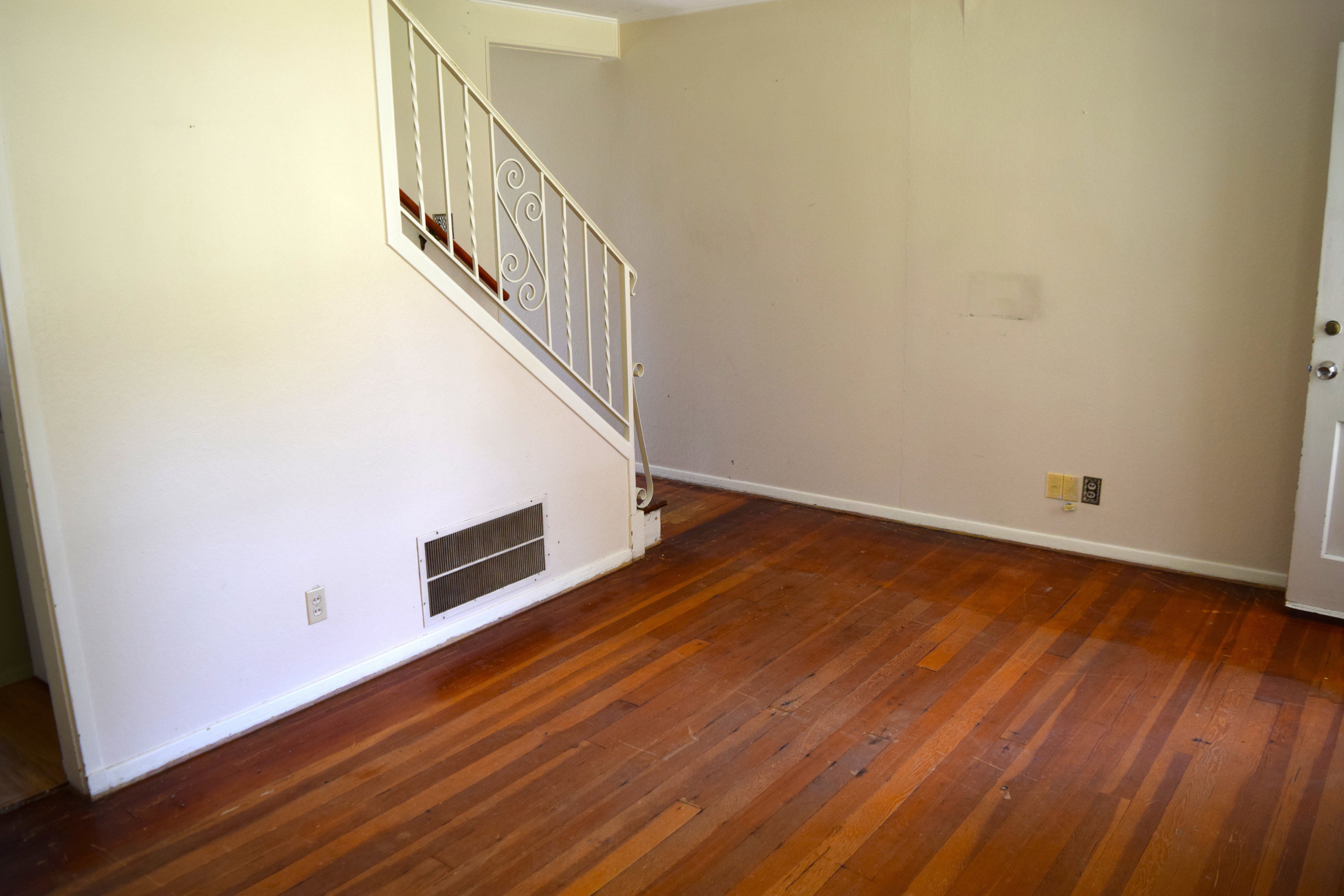 Unfurnished living room featuring baseboards and dark wood-type flooring