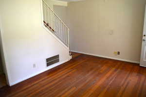 Unfurnished living room featuring baseboards and dark wood-type flooring
