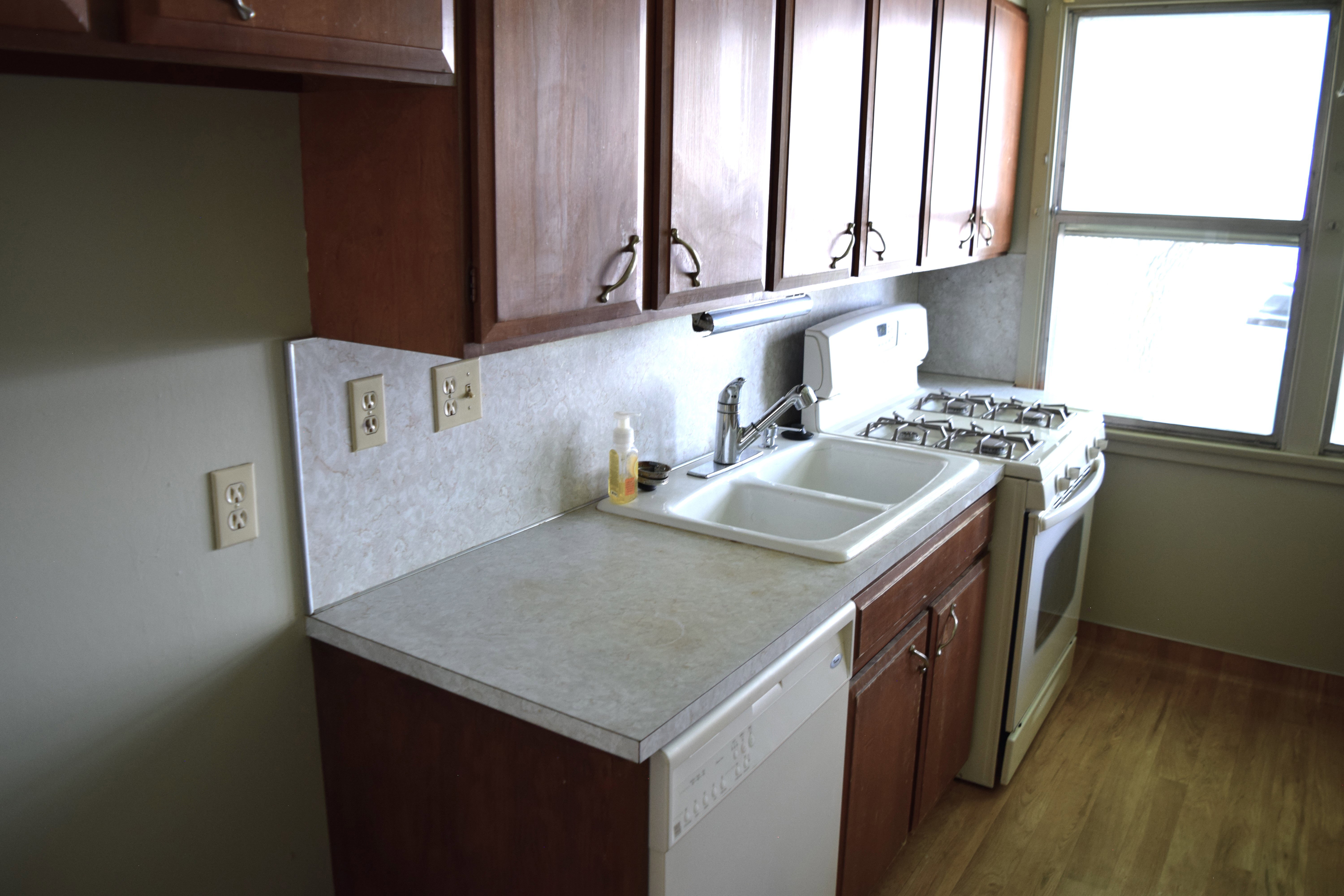 Kitchen with white appliances, light countertops, decorative backsplash, dark wood-style floors, and dark wood finish cabinets